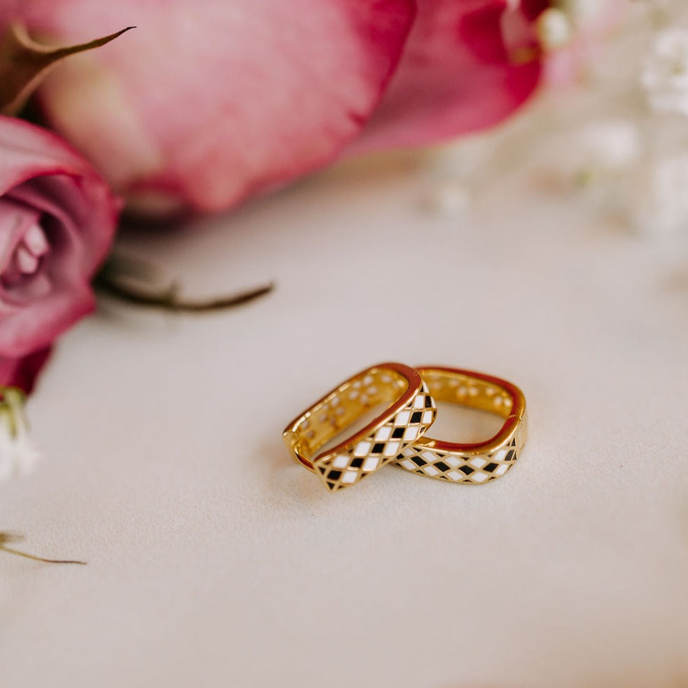 Gold reversible hoop earrings with black-and-white diamond pattern and floral details