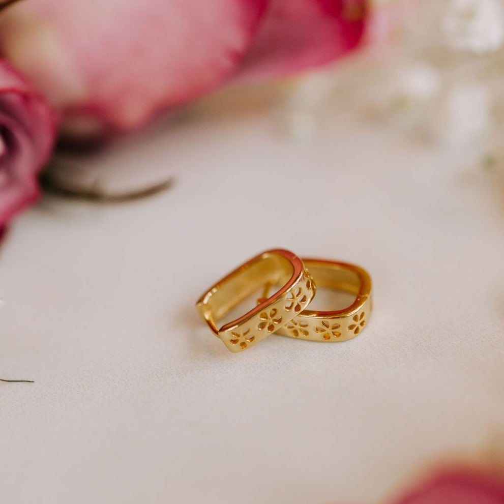 Gold hoop earrings with floral cutout details