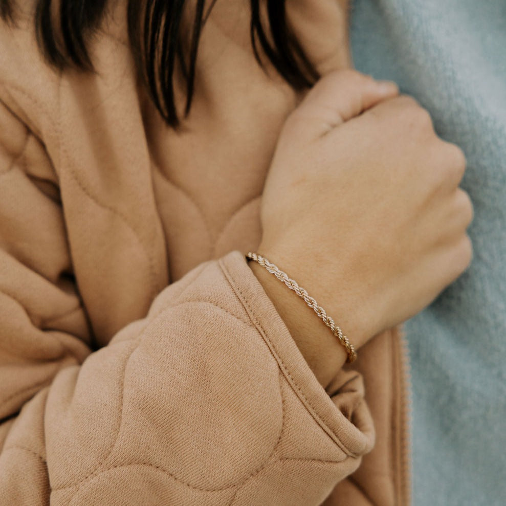 Naomi gold filled rope bracelet worn on wrist, shown above a coat cuff