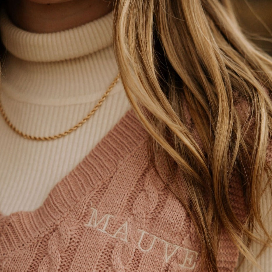 Gold-filled rope necklace worn over a cream ribbed turtleneck.