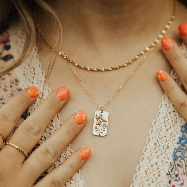 Gold-tone floral pendant necklace shown layered with a short chain