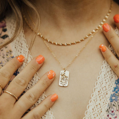 Gold-tone floral pendant necklace shown layered with a short chain