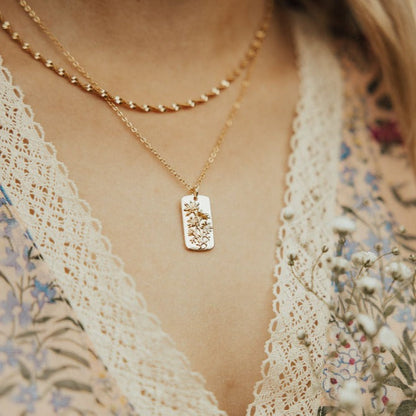 Gold-tone floral pendant necklace worn with a second chain