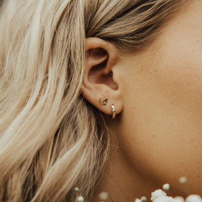 Gold butterfly mini stud worn above a small hoop earring