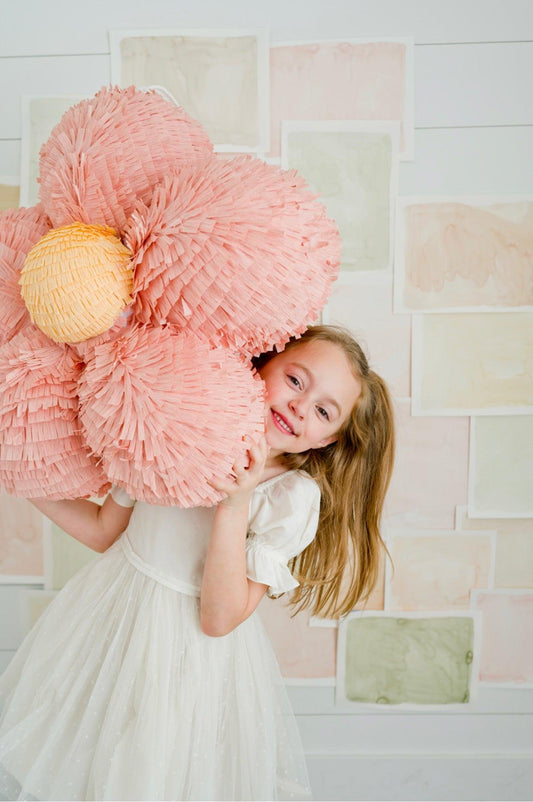 Light pink 3D flower piñata close-up, layered paper petals and yellow round center