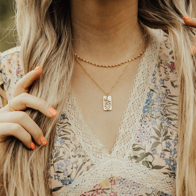 Gold-filled twist necklace worn above a rectangular pendant necklace.