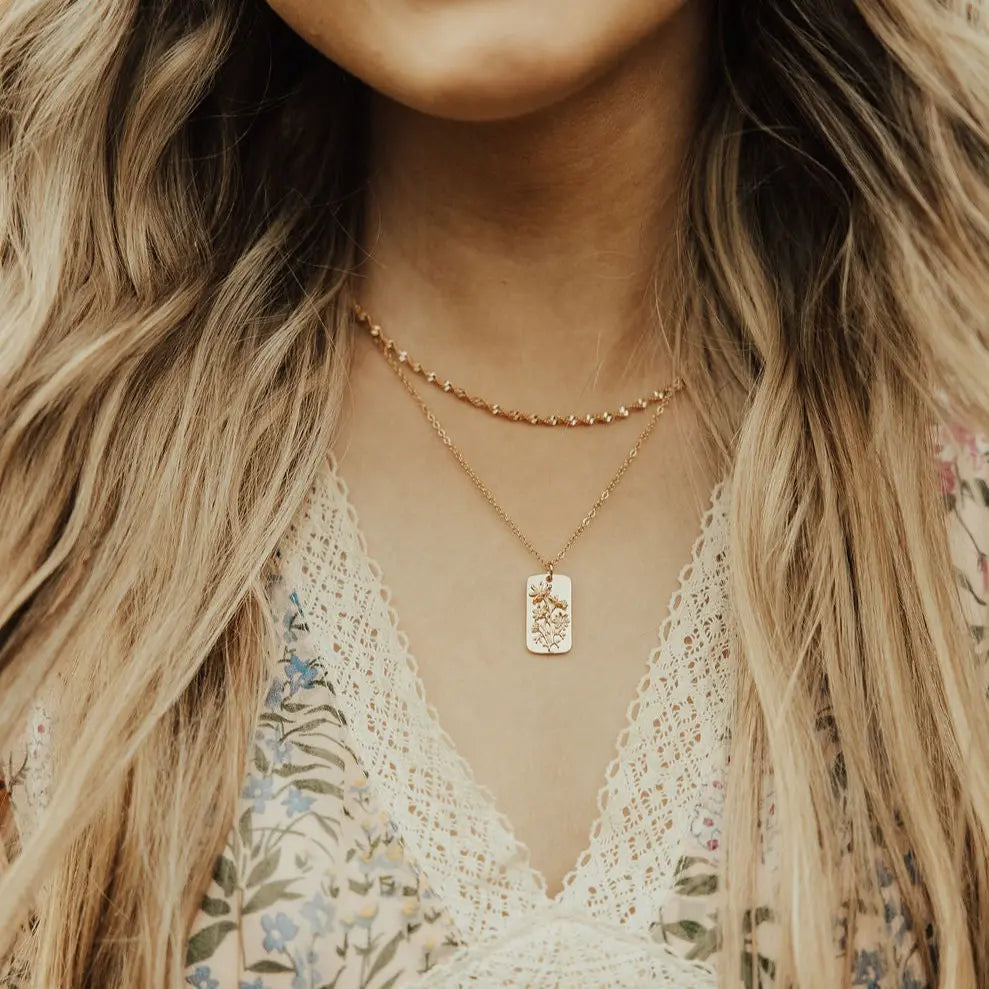 Layered gold-tone necklaces with a small rectangular floral pendant