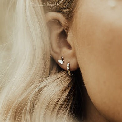Silver butterfly mini stud worn beside a small hoop earring