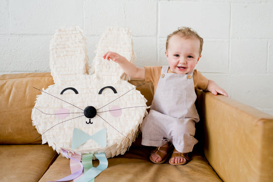 White rabbit piñata with pastel bow, long ears, black nose, whiskers