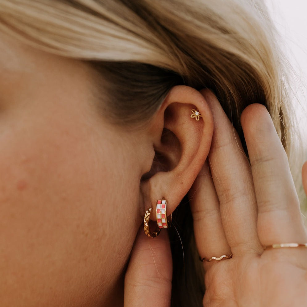 Small gold flower stud worn on the upper ear.
