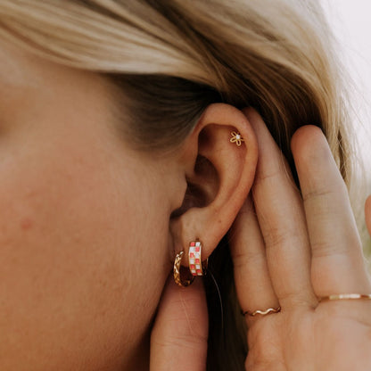 Small gold flower stud worn on the upper ear.