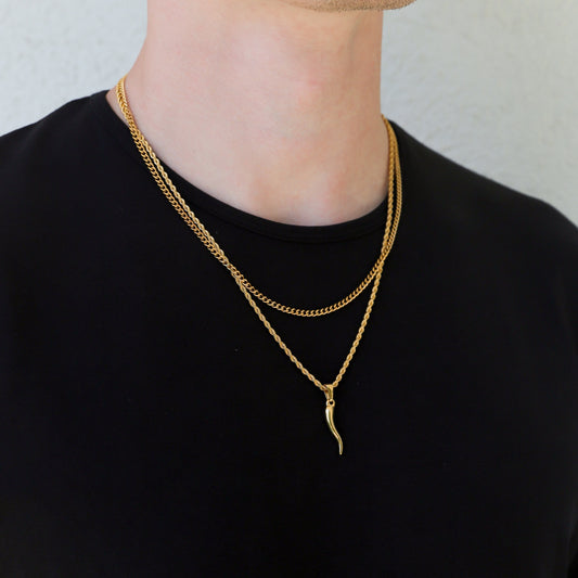Gold horn pendant necklace set on a model in a black shirt