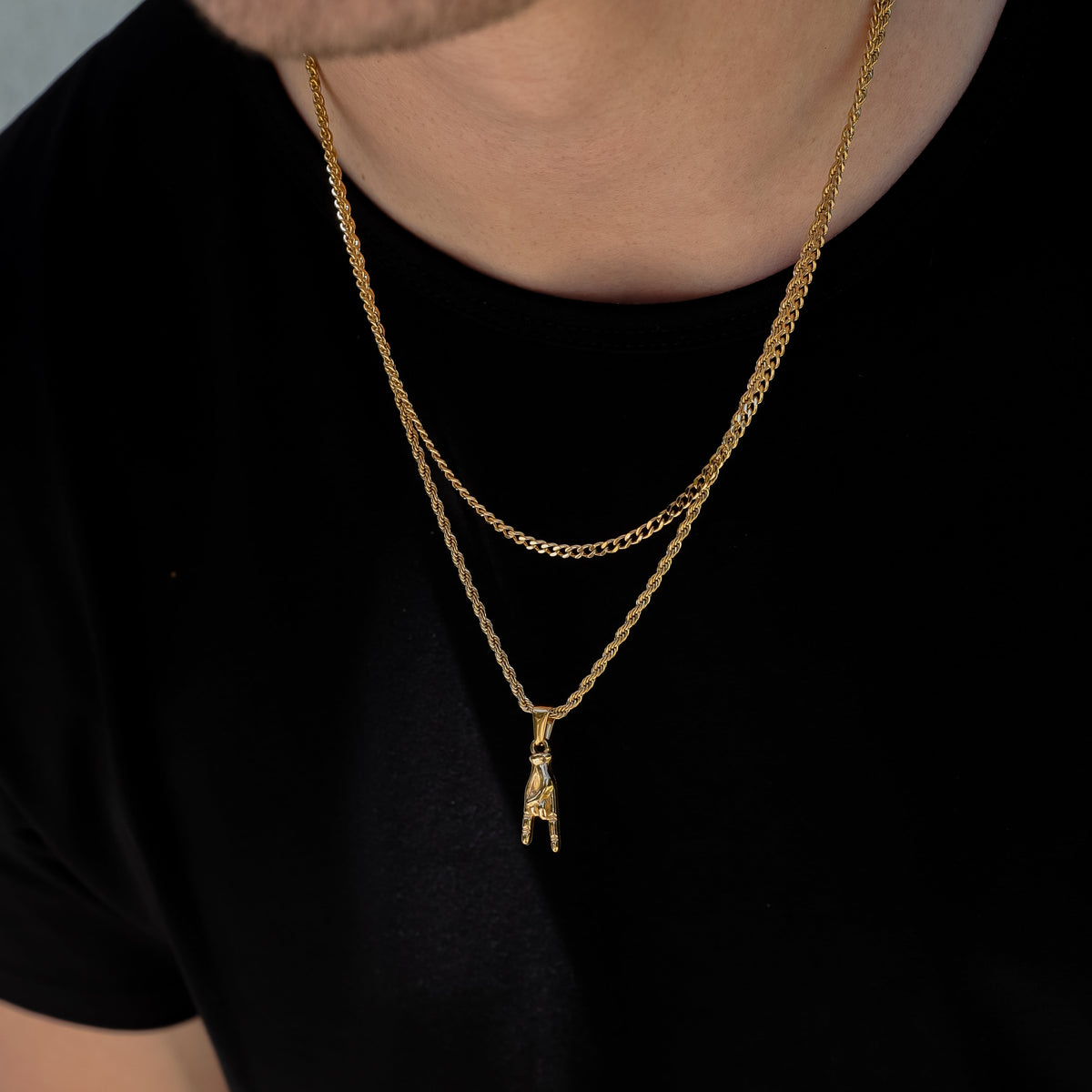 Gold layered necklace set with dangling horn-hand pendant