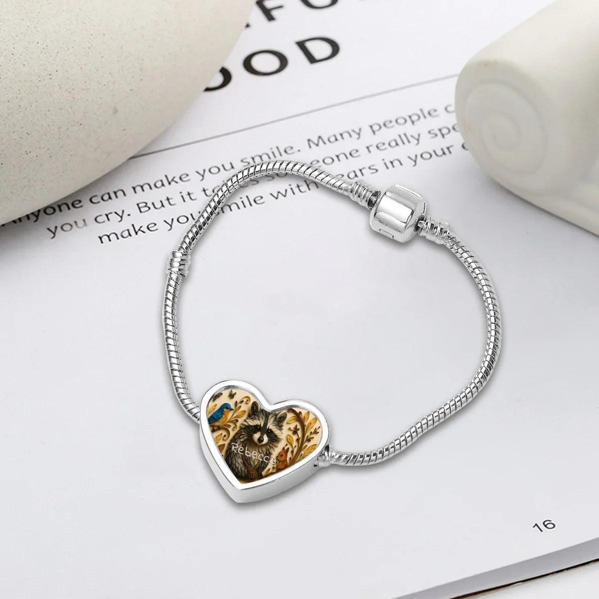 Silver snake chain bracelet with heart pendant showing raccoon artwork and name Rebecca