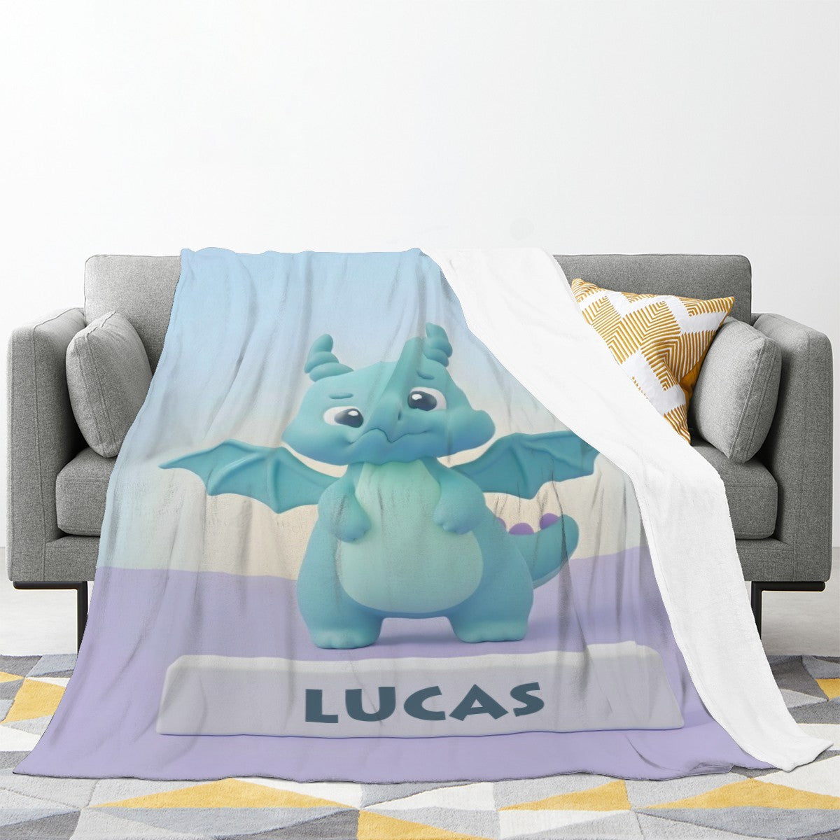 Kids blanket with blue dragon graphic and “LUCAS” text, draped over couch