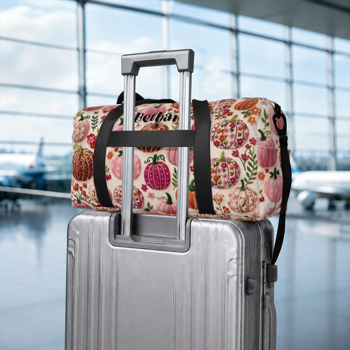 Fruit-pattern duffel bag with “Bethany” patch on top, strapped to a suitcase handle