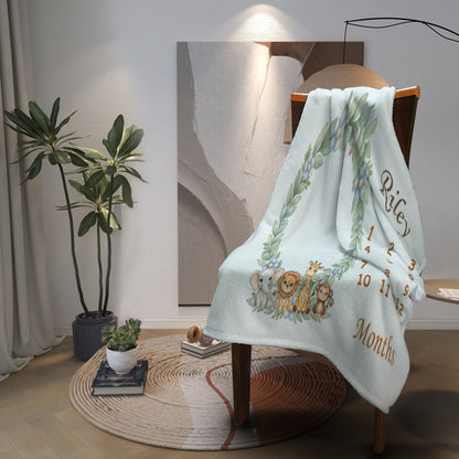 Light blue baby milestone blanket draped over a chair with animal wreath and “Months”