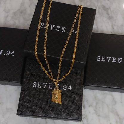 Gold layered chain necklace with Jesus face pendant charm shown on gift bags