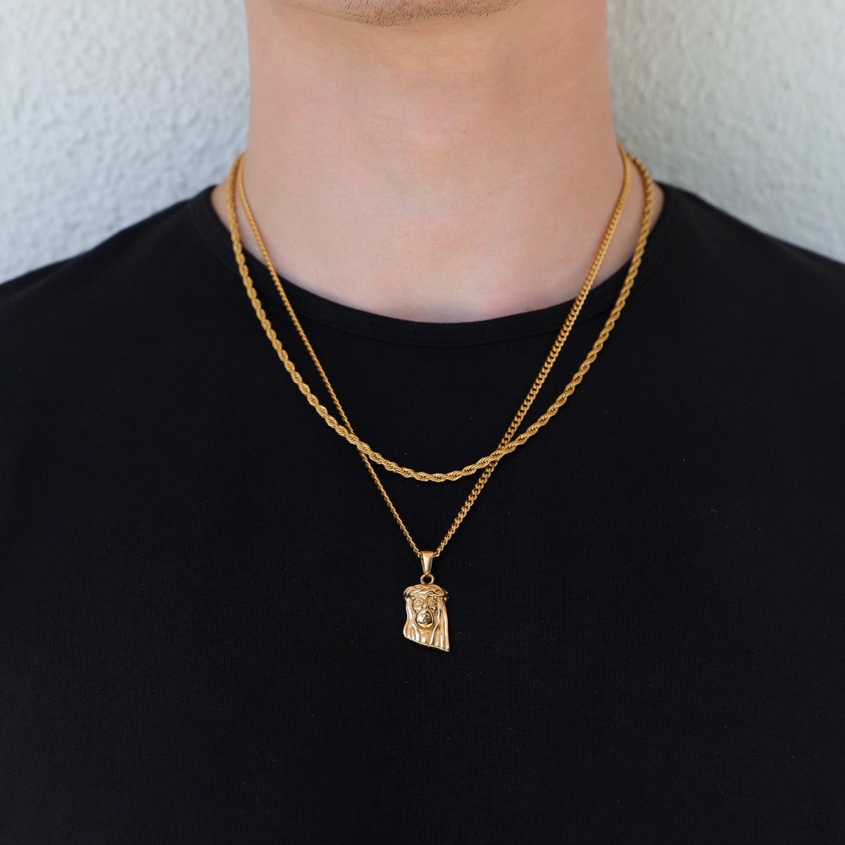 Gold Jesus pendant necklace hanging at center on black crewneck