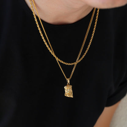 Gold Jesus pendant necklace worn on black shirt, double chain style