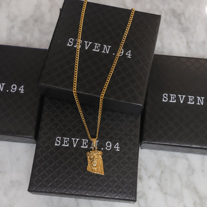 Gold Jesus pendant necklace displayed on shopping bag
