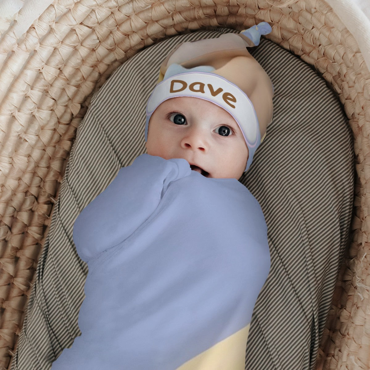 Baby lying wrapped in light blue swaddle and wearing sloth hat with "Dave"