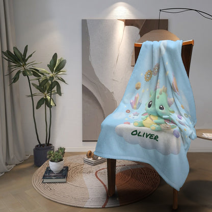 Light blue blanket draped on chair, featuring green dragon and Oliver print