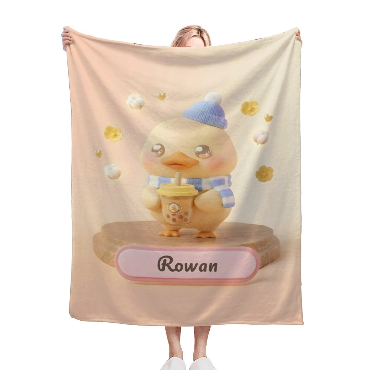 Duck character blanket in light beige with blue hat, yellow flowers, and name banner