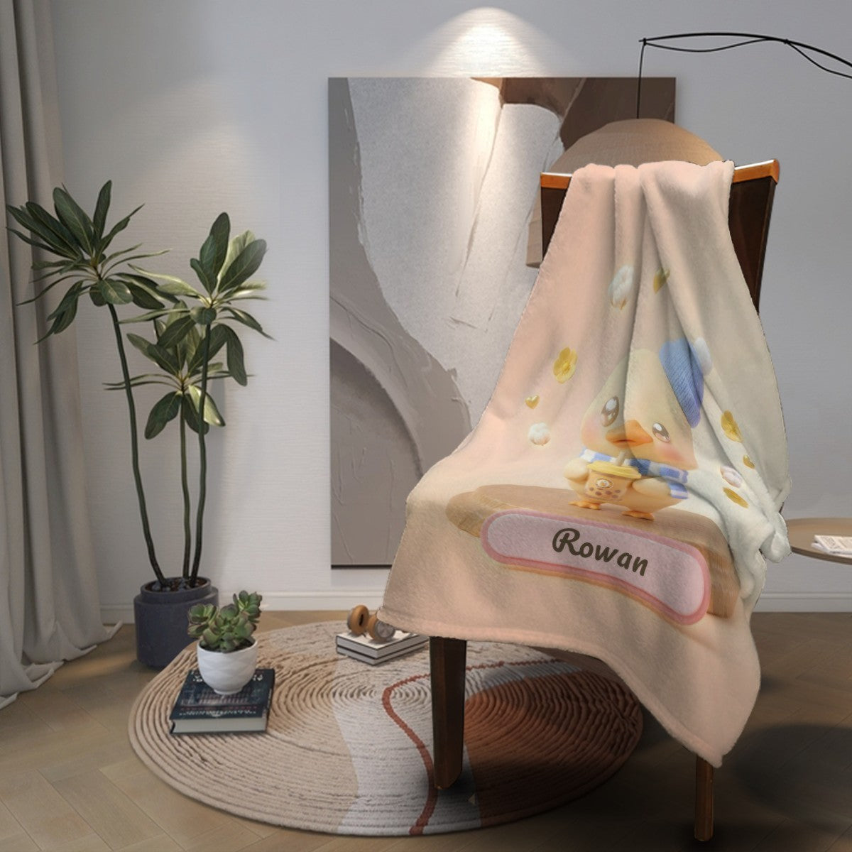 Light beige duck character blanket with blue knit hat and ribbon name badge on chair