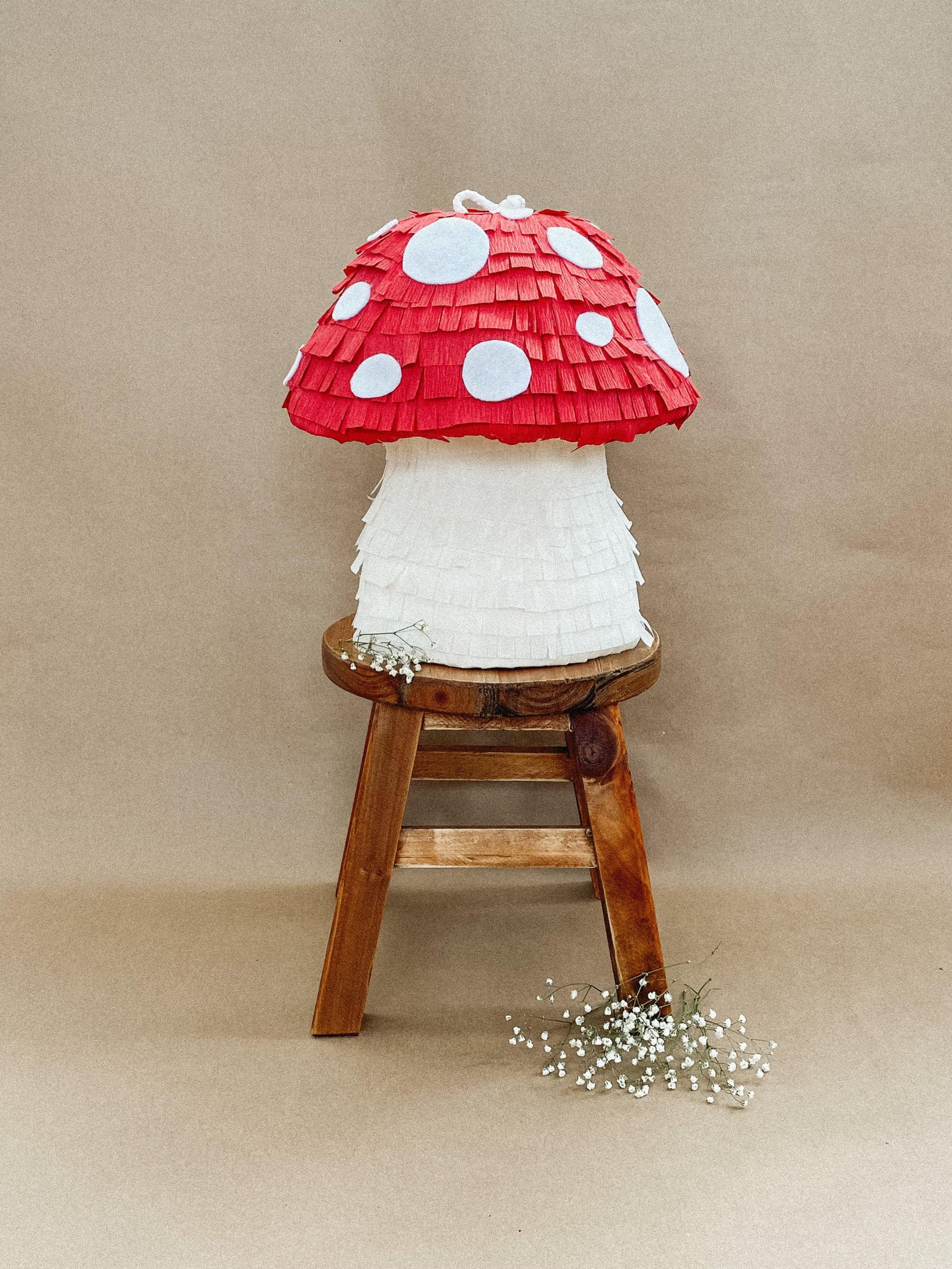 Red mushroom piñata with white spots; layered paper cap and white stem