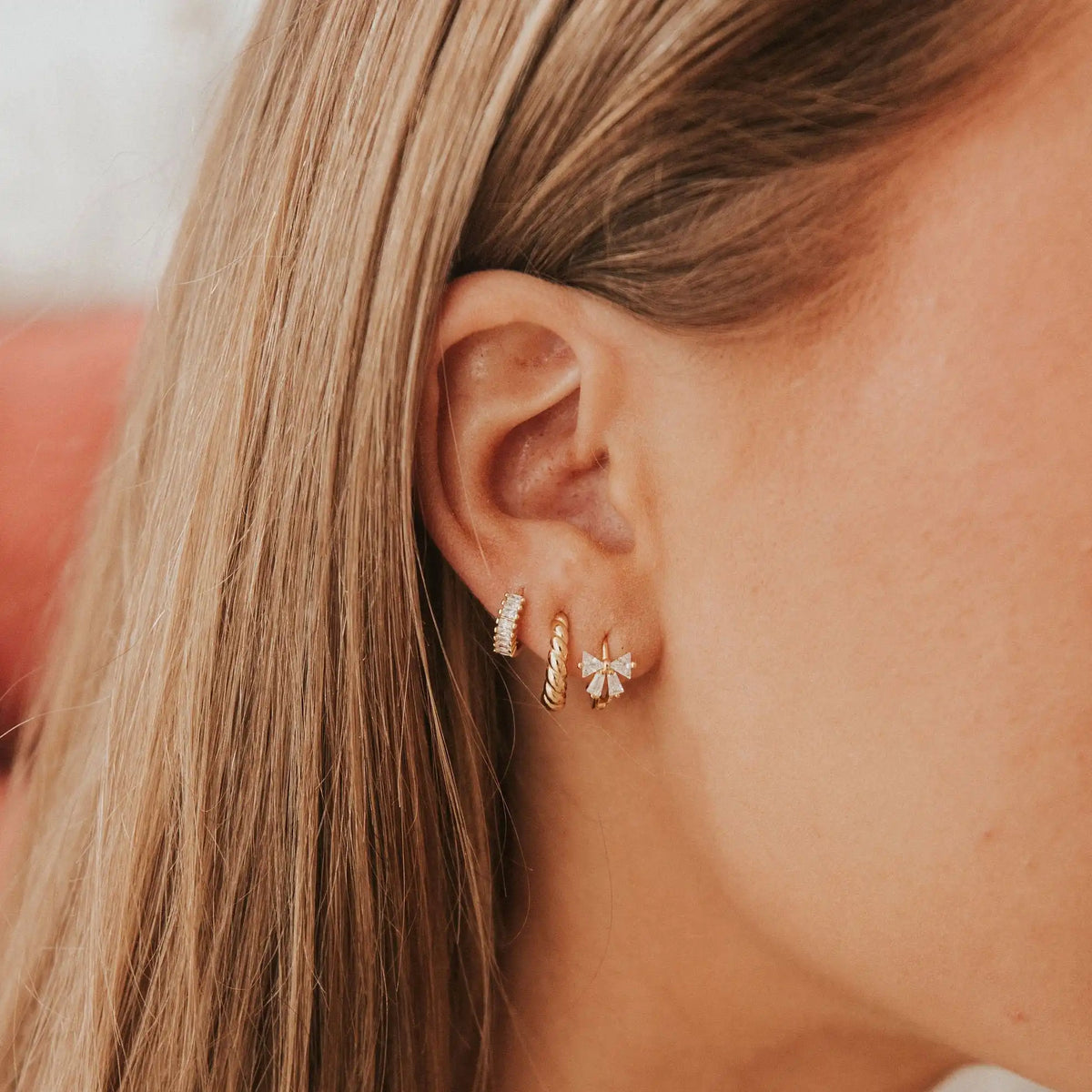 Brooklyn Twist Hoops shown among other gold earrings on an ear