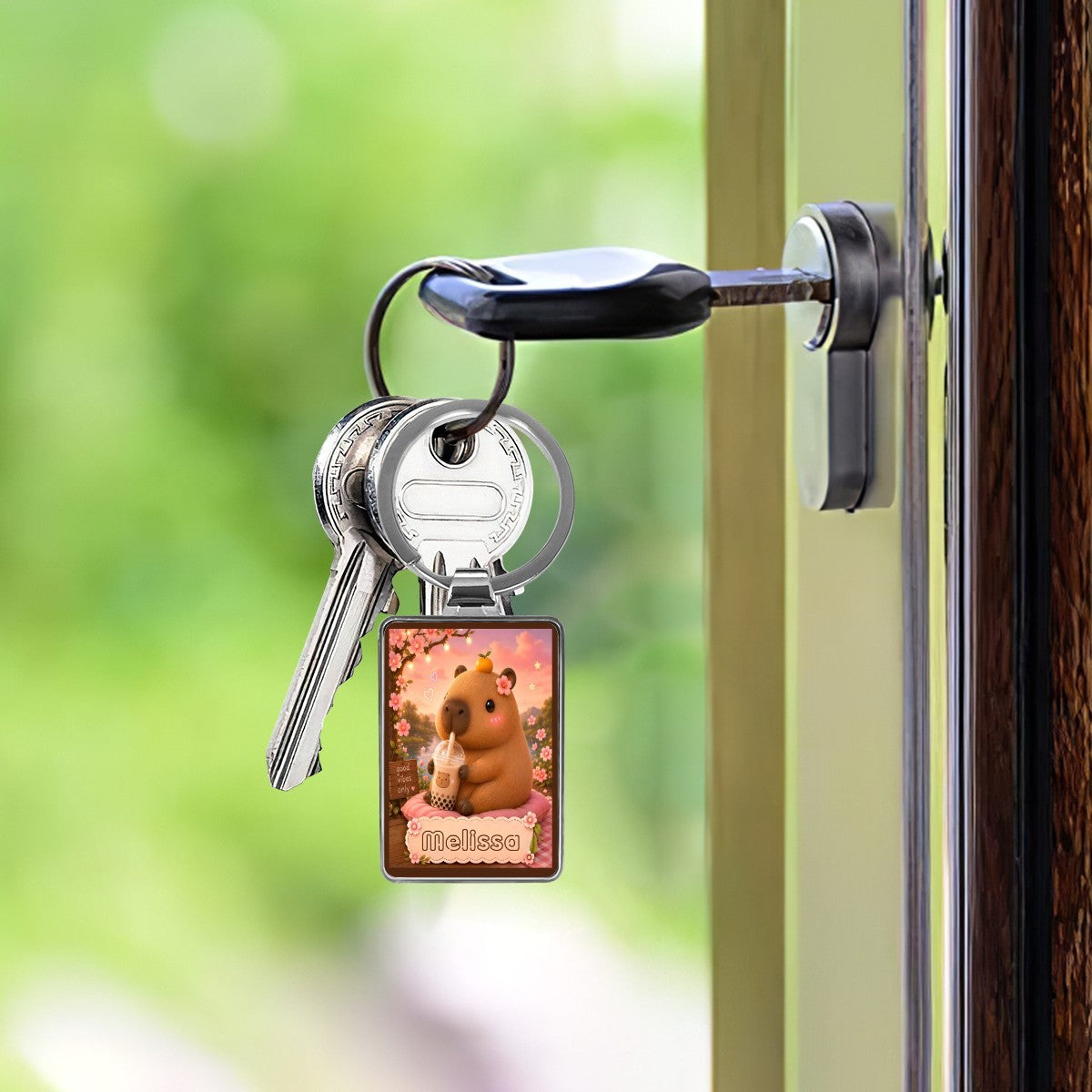 Silver keychain with square photo charm hanging from a door handle