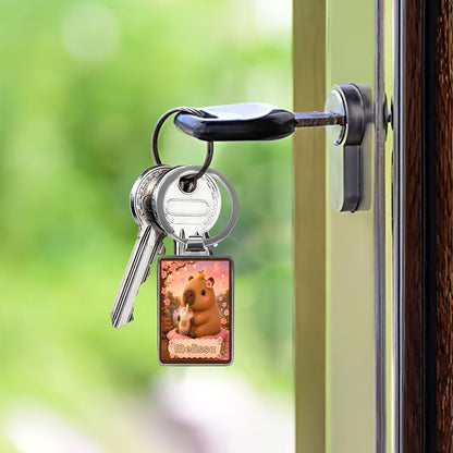 Silver keychain with square photo charm hanging from a door handle