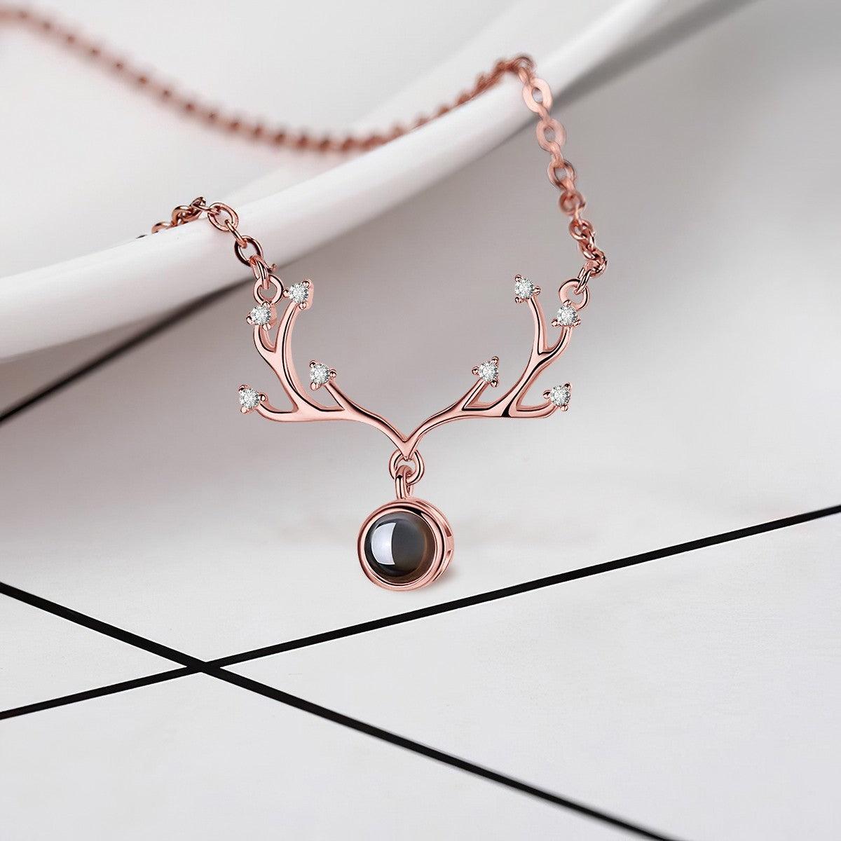 Rose gold antler pendant necklace with round projection locket and crystal antler tips