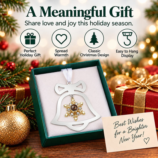 Silver bell ornament with gold snowflake centerpiece, hanging on a ribbon inside a gift box.