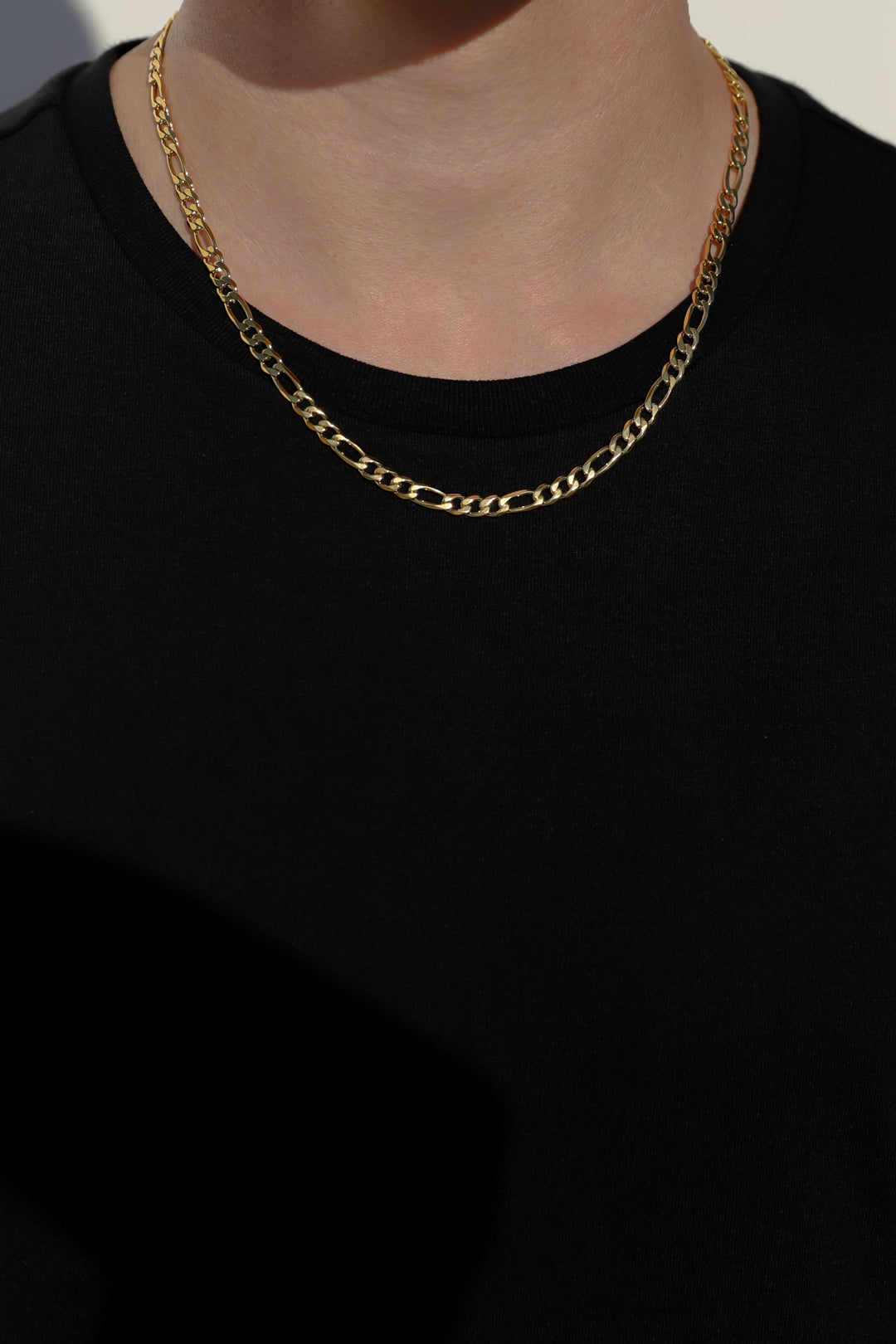 Layered gold-tone Figaro chain necklaces with oval links at collar
