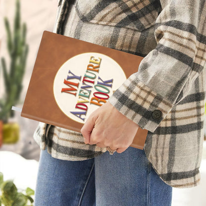 Brown faux-leather notebook held by hand with “My Adventure Book” emblem