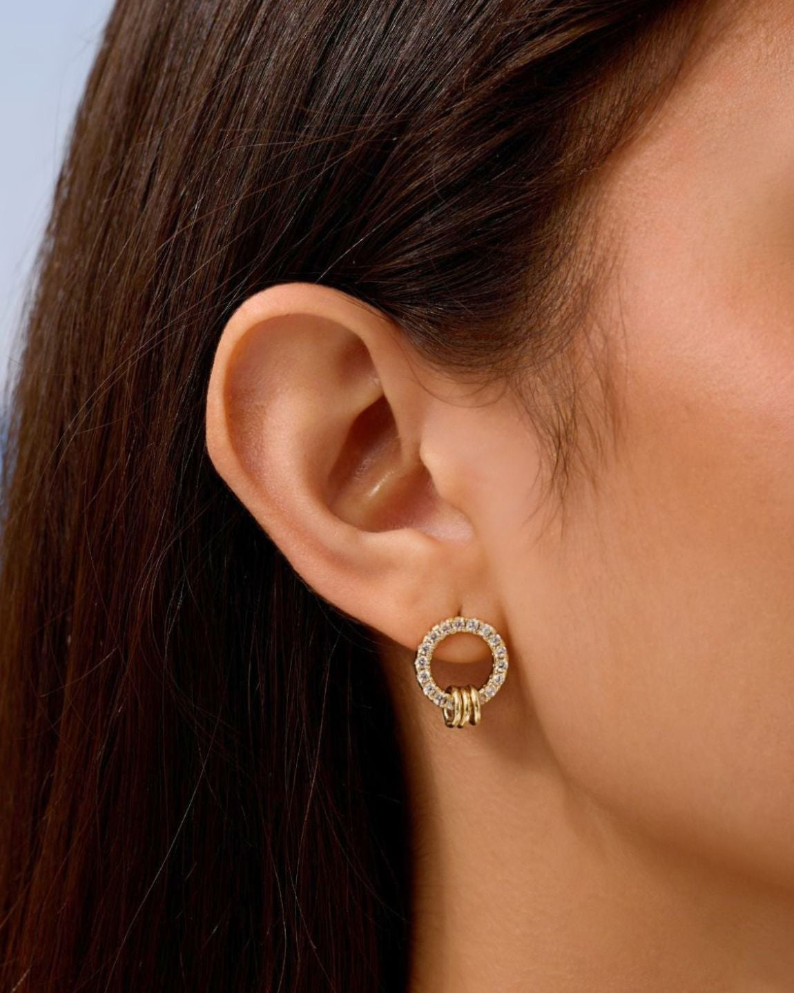 Gold pavé circle stud earring with small linked dangle, worn in ear