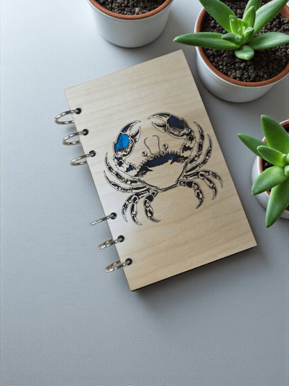 A6 refillable notebook angled view with blue crab illustration on wood-look cover and rings