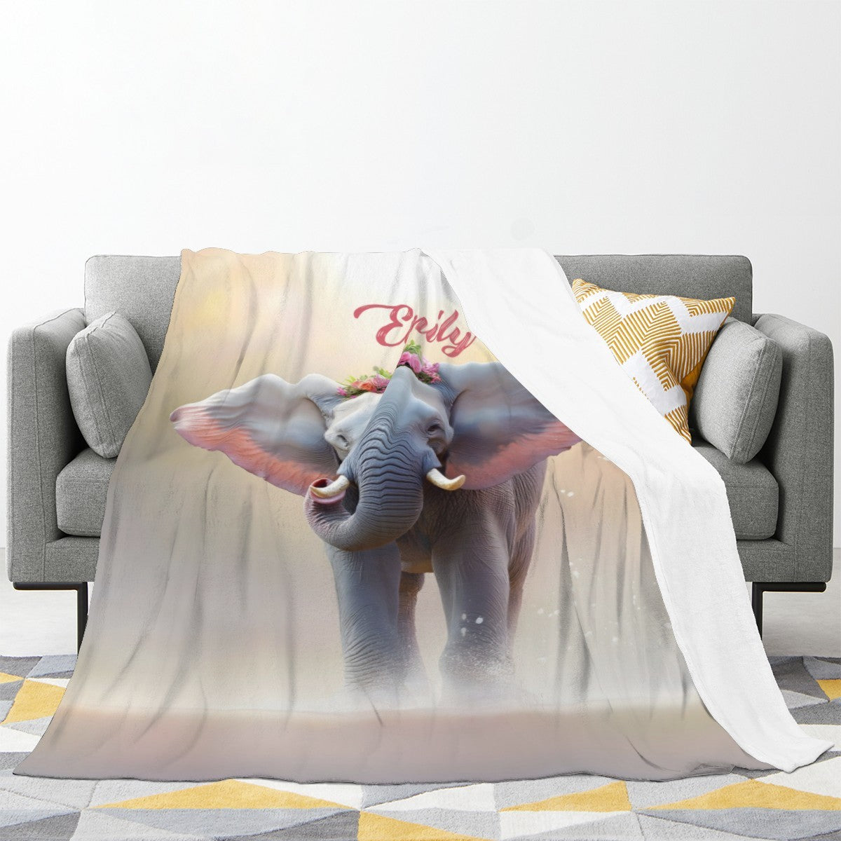 Personalized elephant blanket draped on sofa with 'Emily' name and blue elephant print