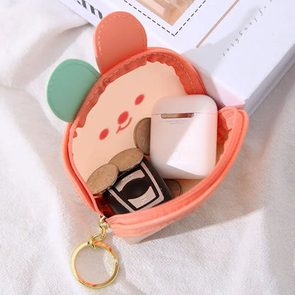 Orange bear-face coin purse open with coins and small electronics, gold key ring