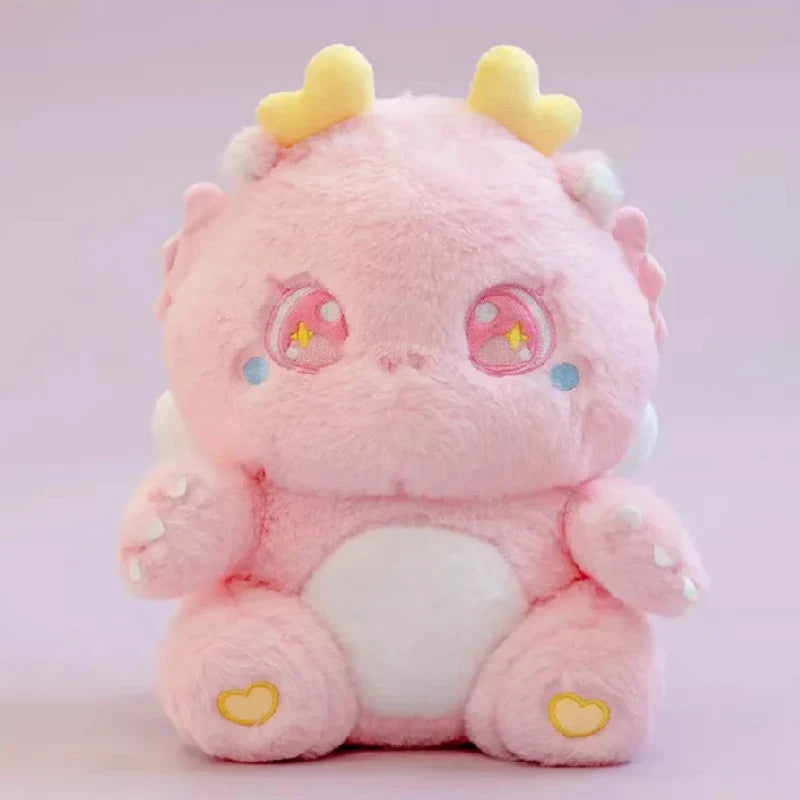 Pink baby dragon plush with star-eye embroidery, yellow horn tips, and heart paws