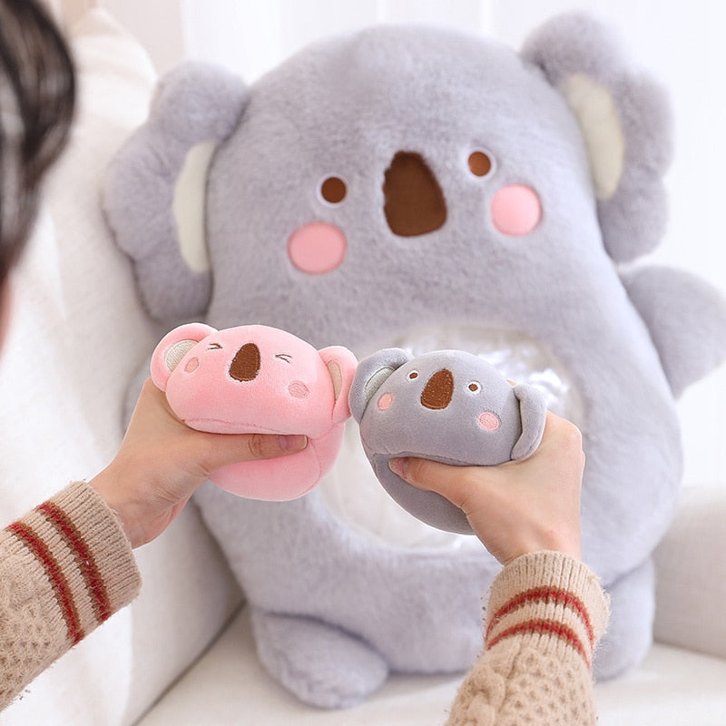 Light gray plush animal pillow with bear-like face; hands holding pig and bear plush