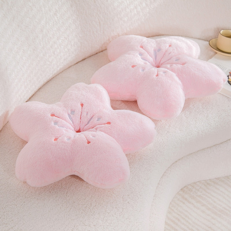 Pink plush cherry blossom pillow with soft petal sections and embroidered blossom stamen.