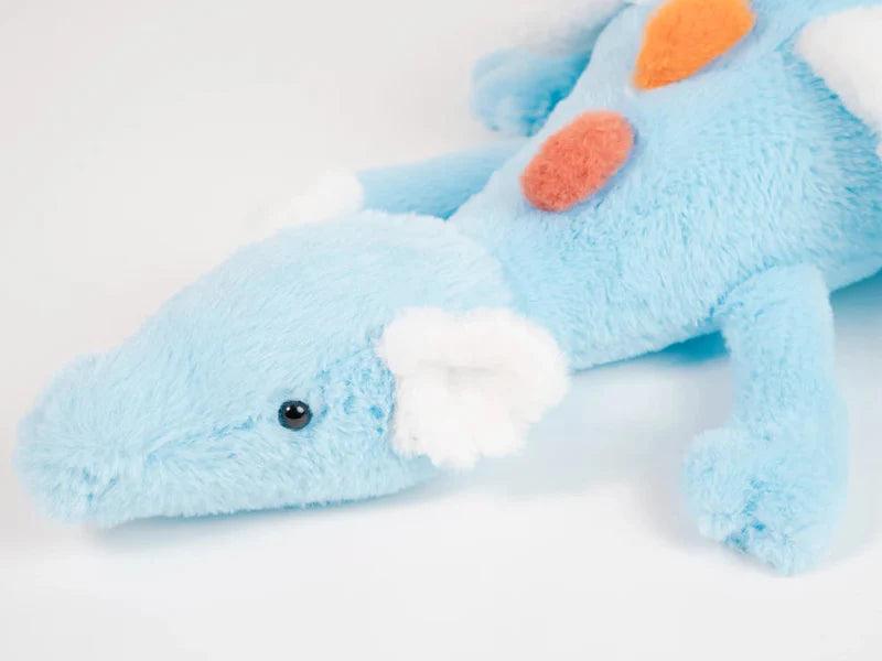 Rainbow dragon plush toy close-up, light blue head with white snout and orange pom on back