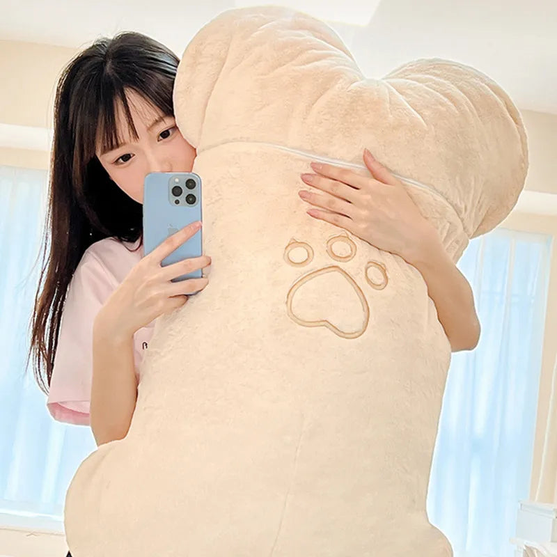Cream plush animal with embroidered paw pattern on large hood, held close by child