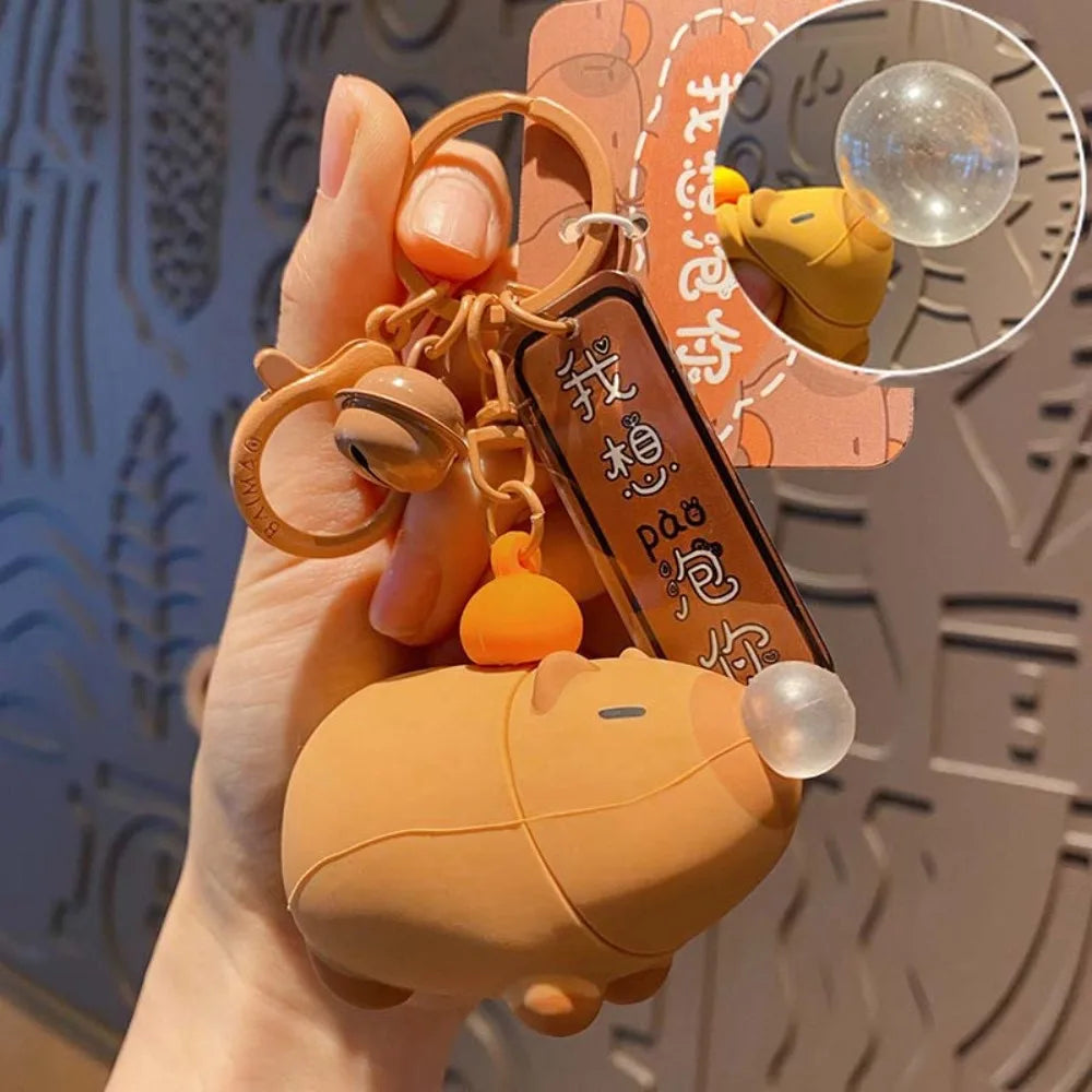 Capybara plush keychain in hand, squeeze bubble dome on side with metal rings