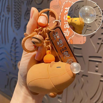 Capybara plush keychain in hand, squeeze bubble dome on side with metal rings