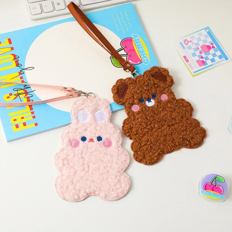 Pink and brown plush animal photo card sleeves with wrist straps on desk