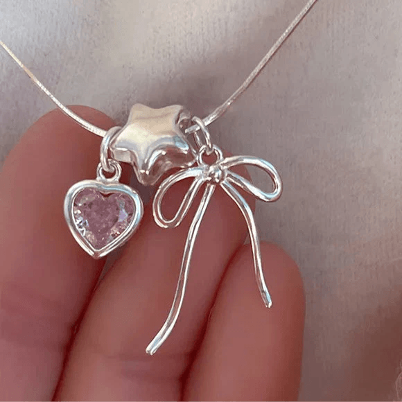 Silver heart and bow charm necklace detail with pink heart stone and ribbon loops